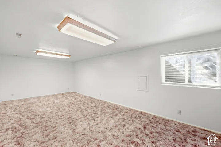 Carpeted flooring, white painted walls, recessed window, and flush-mounted ceiling light fixtures