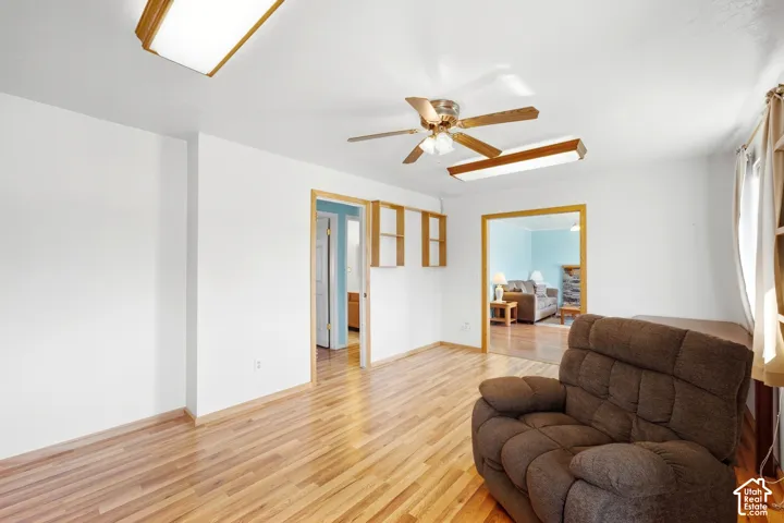 Wood-finish flooring, white walls, and a ceiling fan with integrated lighting