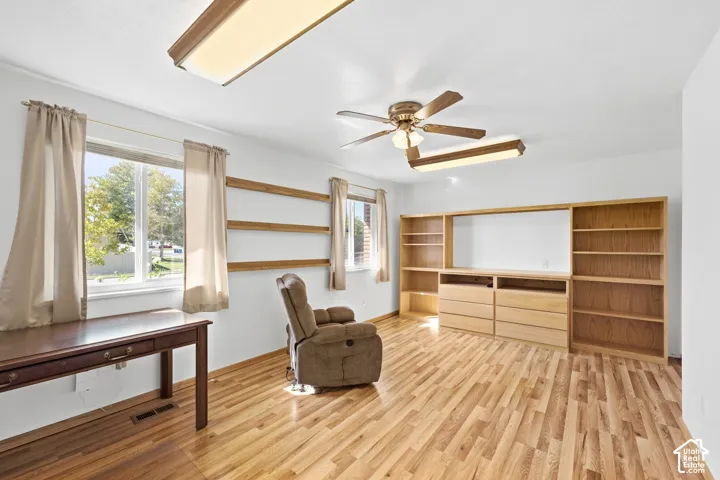 Wood-finish flooring, built-in shelving, built-in storage, ceiling fan, and multiple windows