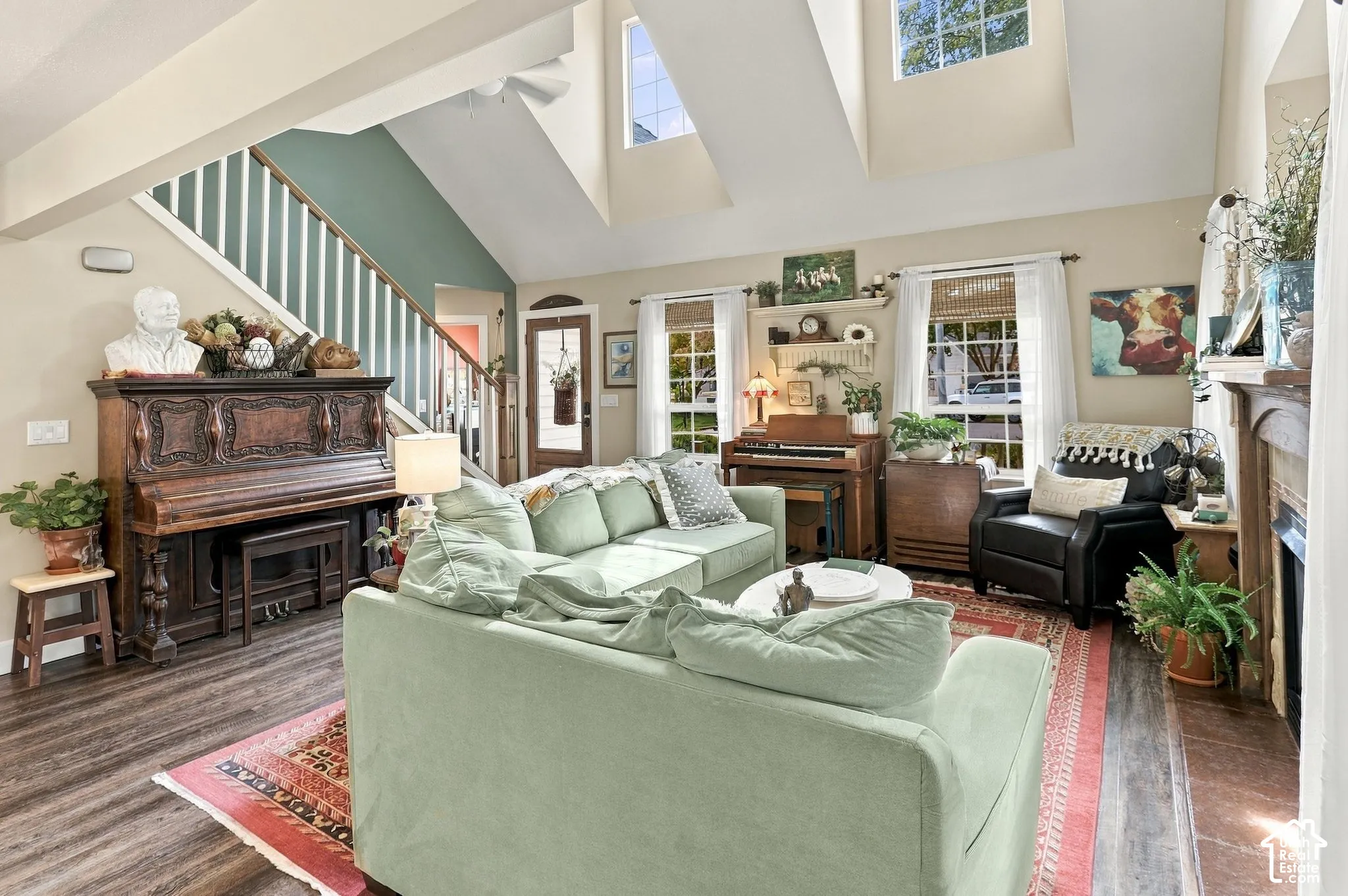 Vaulted ceiling with skylights, wood-finish flooring, staircase with white risers, and large windows with blinds