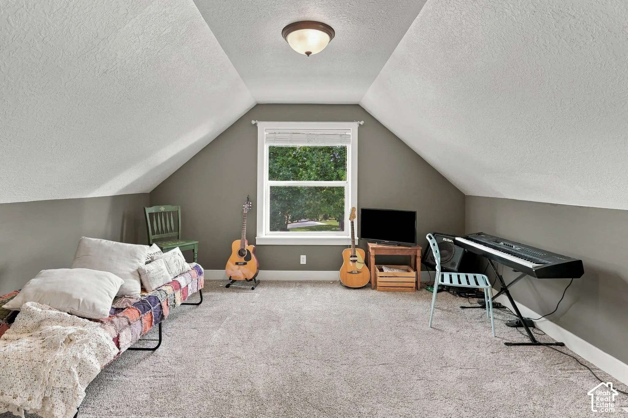 Carpeted room featuring a single window with white trim, sloped ceilings, and a flush-mount ceiling light