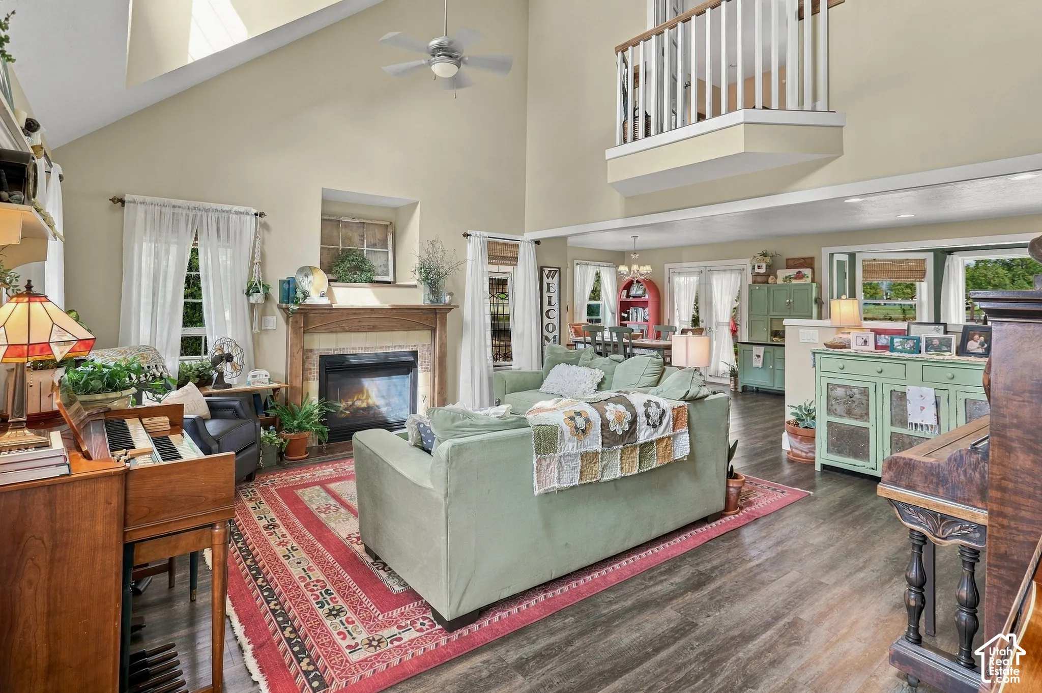 Vaulted ceiling, wood-finish flooring, built-in fireplace with wood mantel, ceiling fan, and upper-level interior balcony