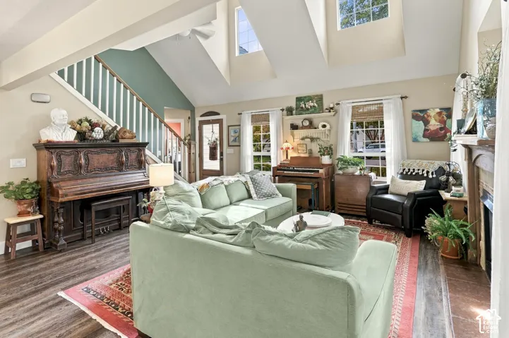Vaulted ceiling with skylights, wood-finish flooring, staircase with white risers, and large windows with blinds
