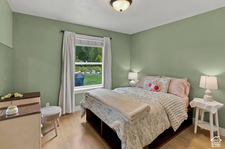Wood-finish flooring, recessed ceiling light, window with outdoor scenery, and light green wall finish