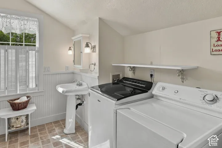 Pedestal sink, wall-mounted medicine cabinet with sconces, white beadboard wainscoting, louvered window shutters, and tiled flooring