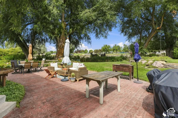 Expansive stamped concrete patio with mature shade trees, bordering a substantial grass lawn