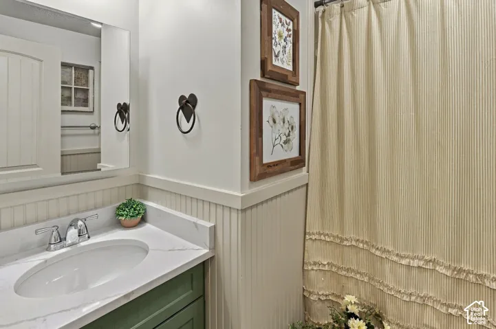 Vanity with a white countertop and oval sink, beadboard wainscoting, and wall-mounted mirror