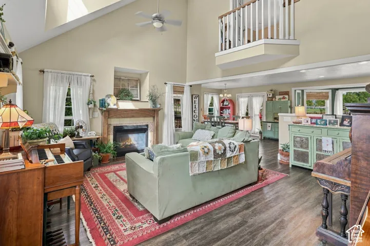 Vaulted ceiling, wood-finish flooring, built-in fireplace with wood mantel, ceiling fan, and upper-level interior balcony
