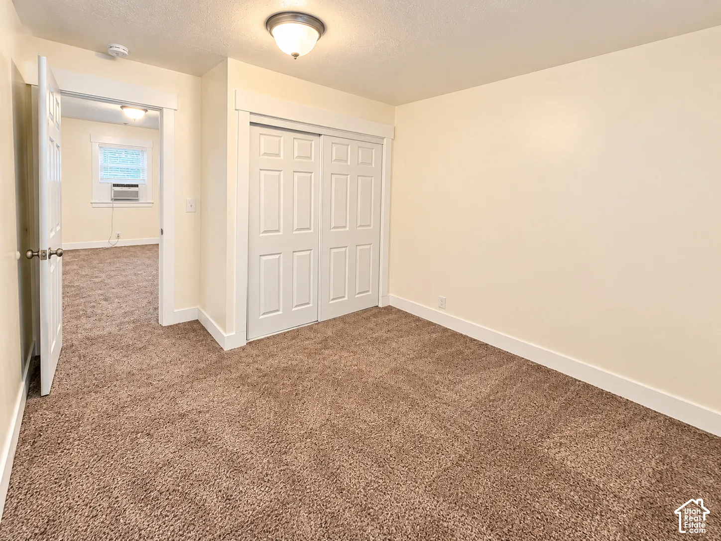 Neutral interior featuring wall-to-wall carpeting, six-panel sliding closet doors, and a flush-mount ceiling light fixture