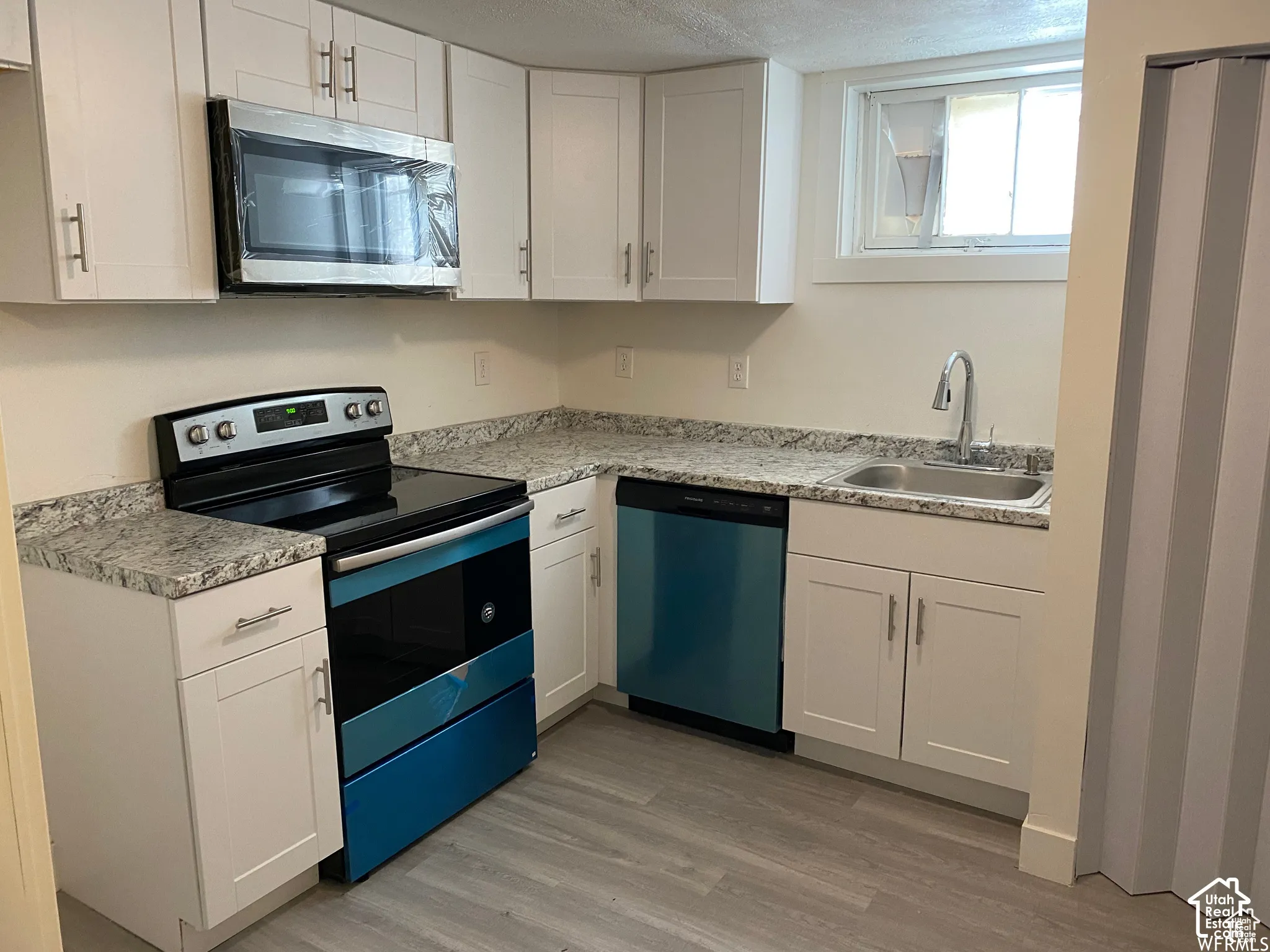 Kitchen featuring white shaker-style cabinetry, granite-finish countertops, stainless steel appliances, and a stainless steel sink with a gooseneck faucet