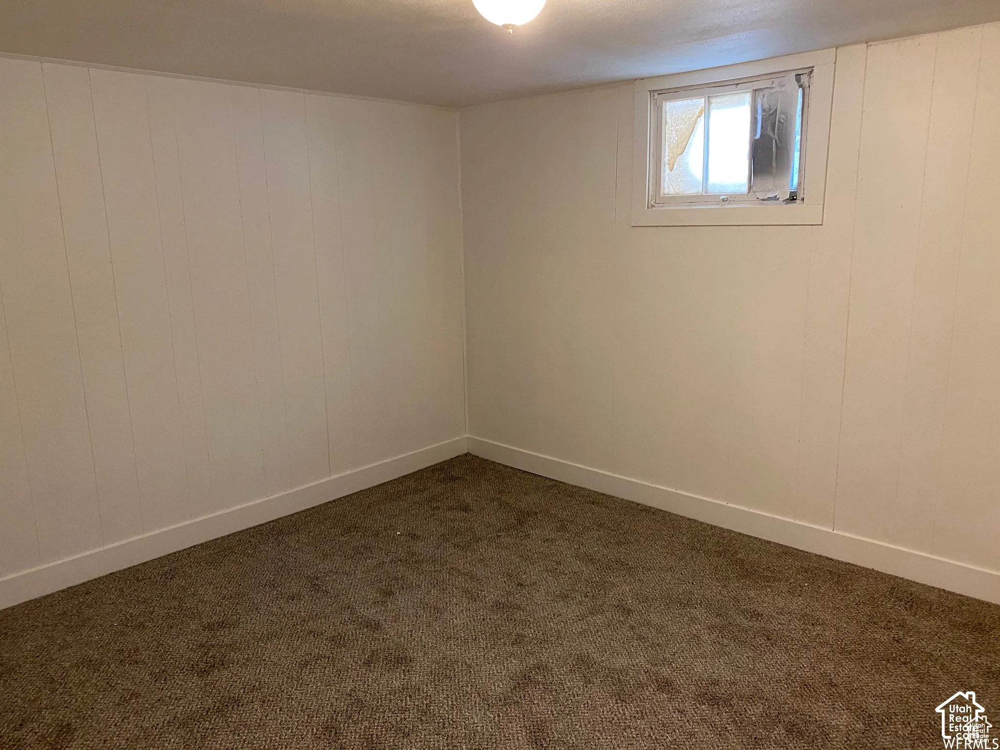 Carpeted flooring with white paneling walls and a single-pane window