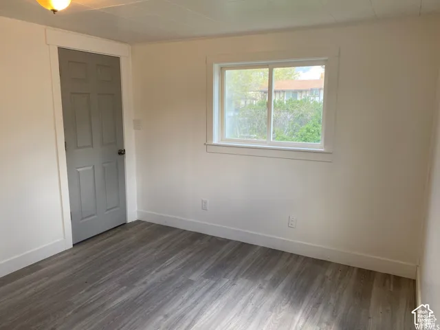 Hardwood-finish flooring, white painted walls, white trim, and a window with white casing