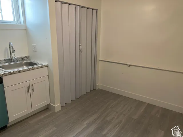 Compact kitchen area featuring a stainless steel sink, granite-style countertop, and white cabinetry