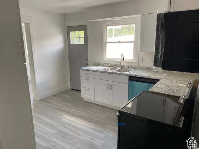 White shaker cabinetry, light-toned wood-finish flooring, and light-toned countertop surfaces