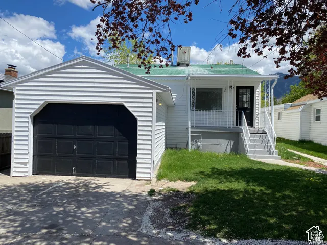 Detached garage with white siding and a black garage door