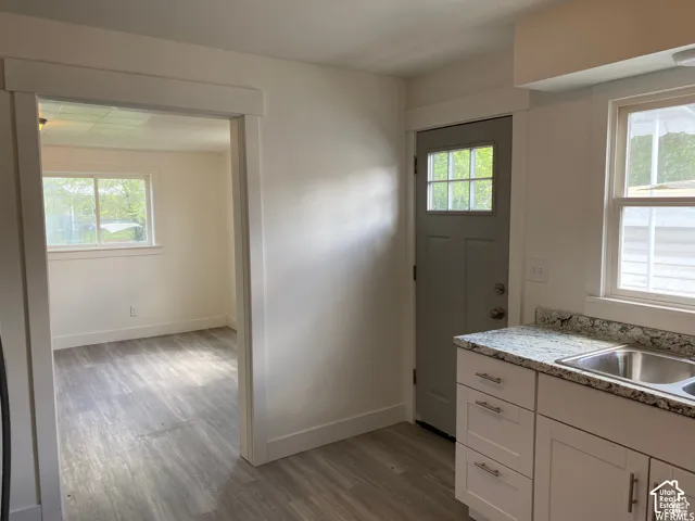 White cabinetry with silver-tone hardware, a stainless steel double-basin sink, and speckled countertops