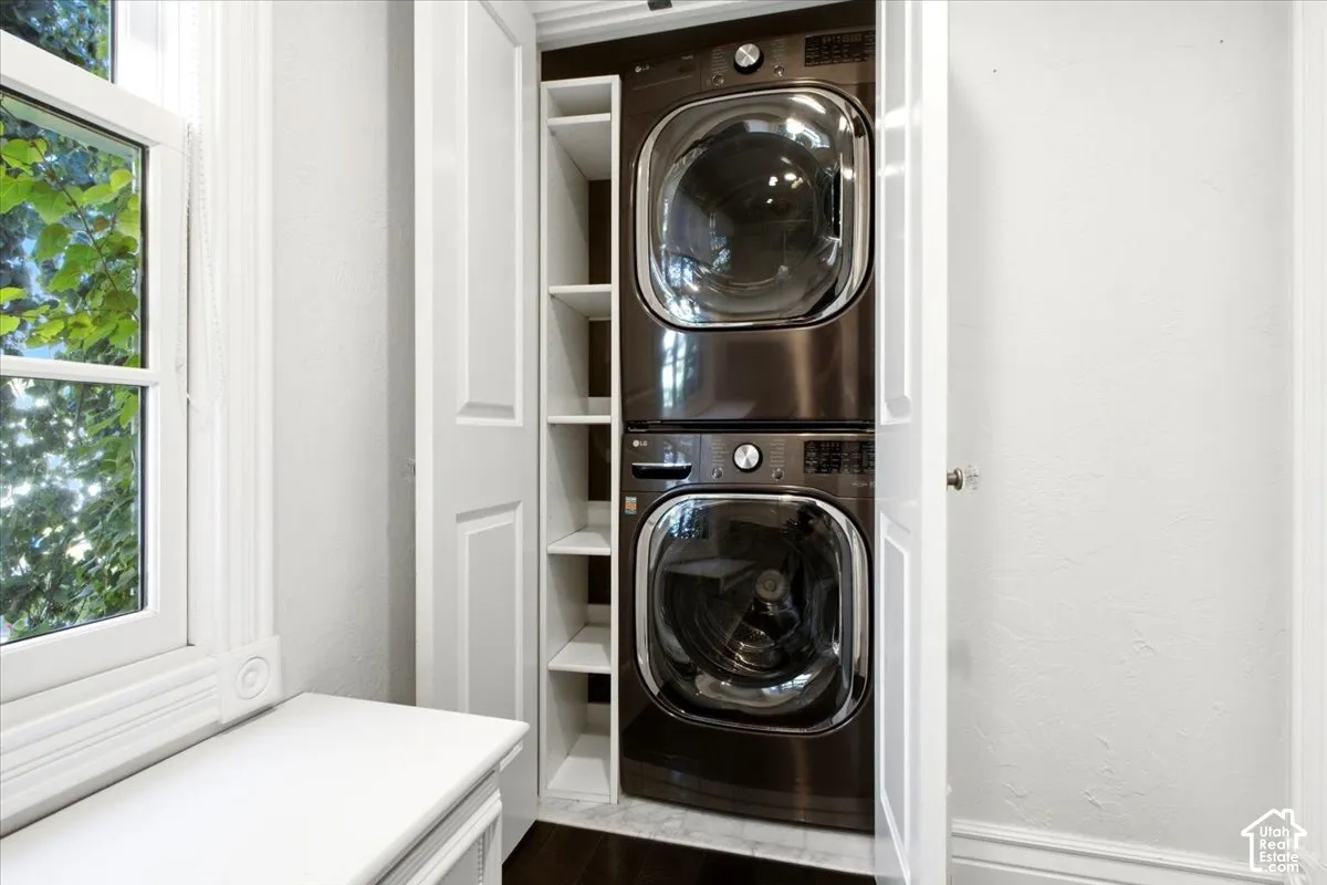 Stacked laundry appliances with built-in shelving, white paneled doors, and a window with white trim