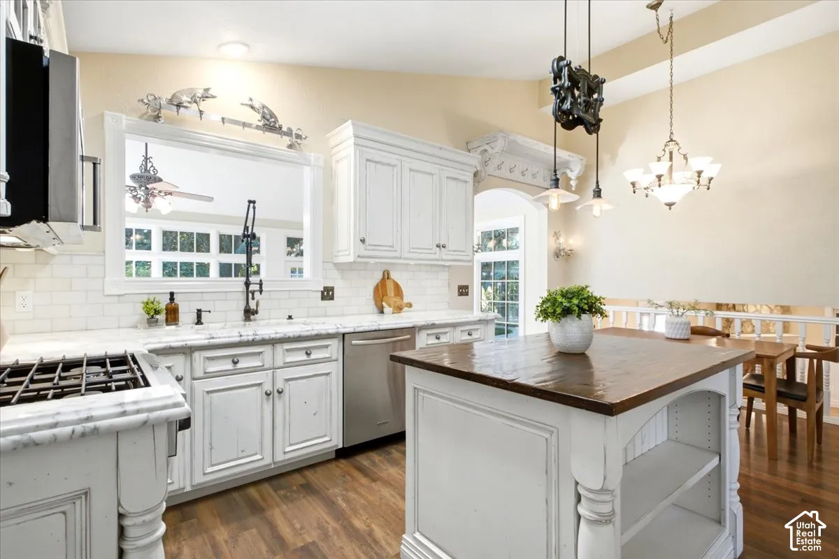 Kitchen featuring distressed white cabinetry, stone countertops, subway tile backsplash, and a large central island with a wood-finish top