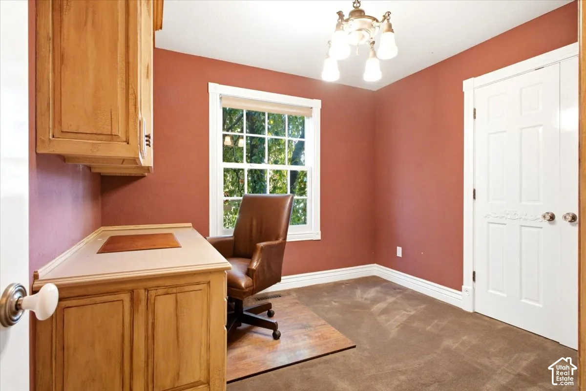 Built-in cabinetry with counter space, window with exterior view, decorative door, overhead lighting fixture, and carpeting
