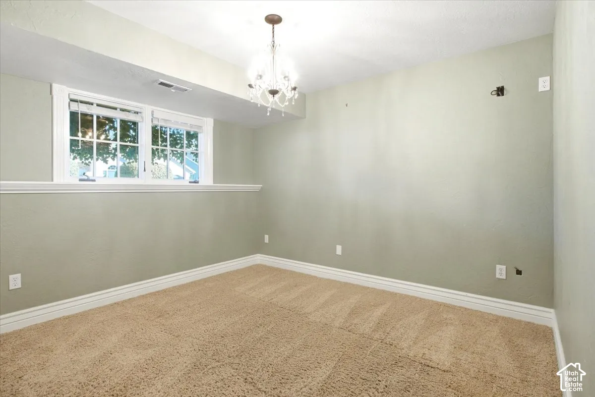 Plush carpet, neutral wall paint, white trim, and a chandelier lighting fixture