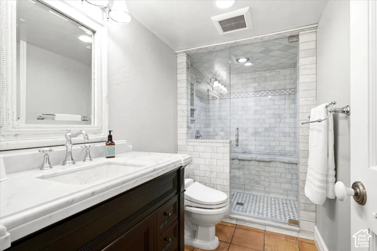 Vanity with white countertop and integrated sink, chrome faucet, framed mirror, and dark wood-finish cabinetry