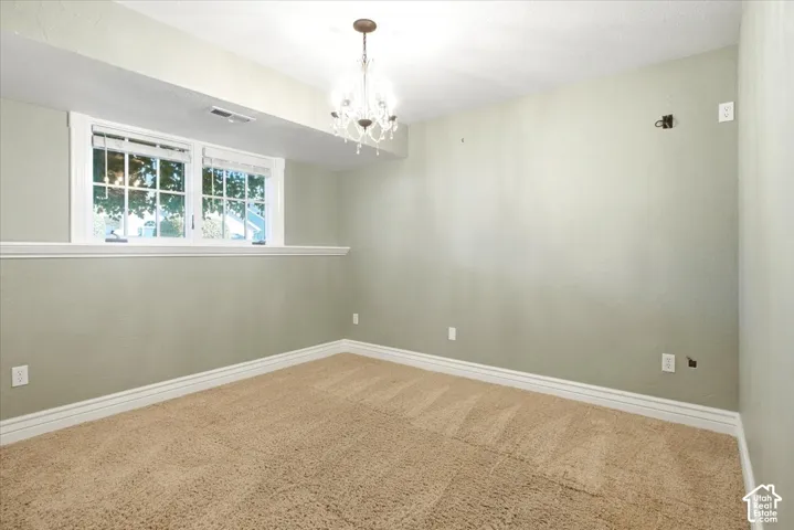 Plush carpet, neutral wall paint, white trim, and a chandelier lighting fixture
