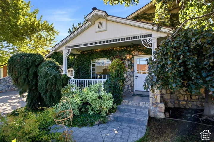 Stone exterior with established greenery and a covered front porch featuring decorative white railings