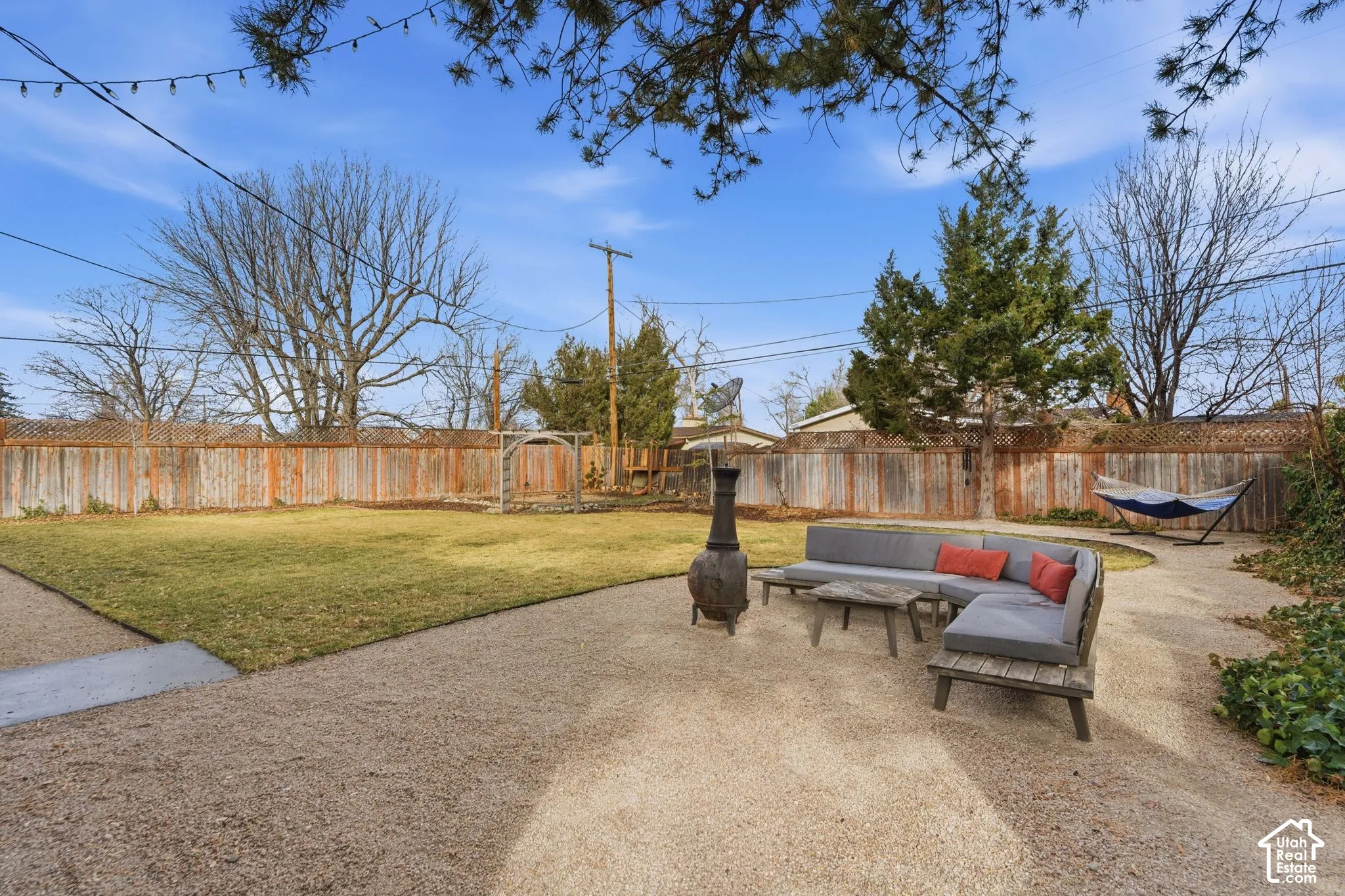 Expansive backyard featuring a gravel patio, manicured lawn, and wood privacy fencing