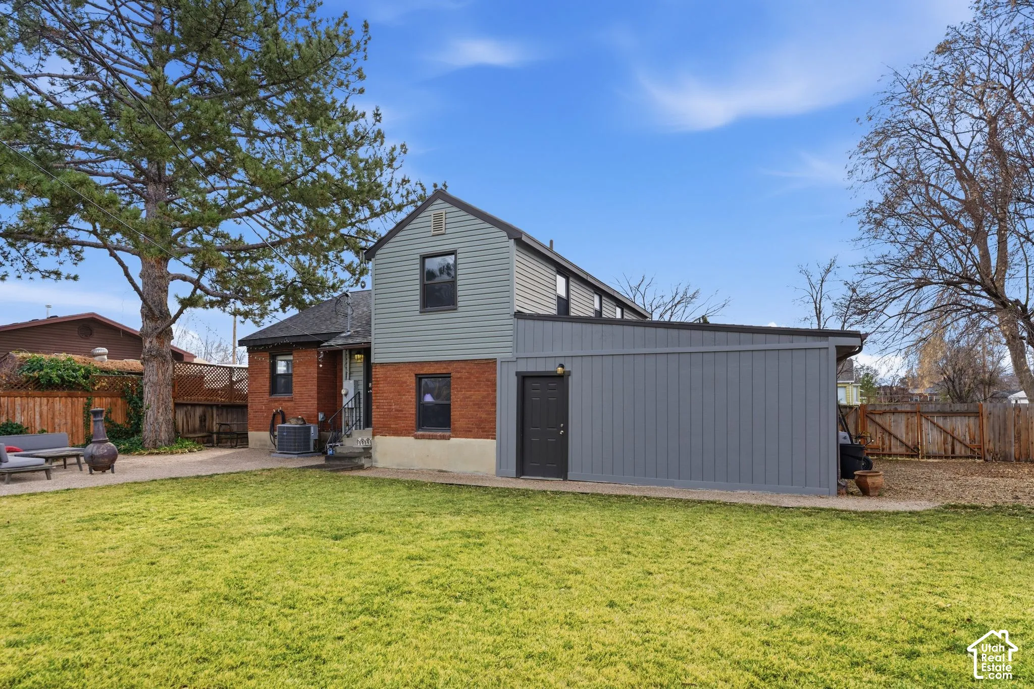 Expansive rear yard with a green lawn, brick and siding exterior, and a built-in storage structure