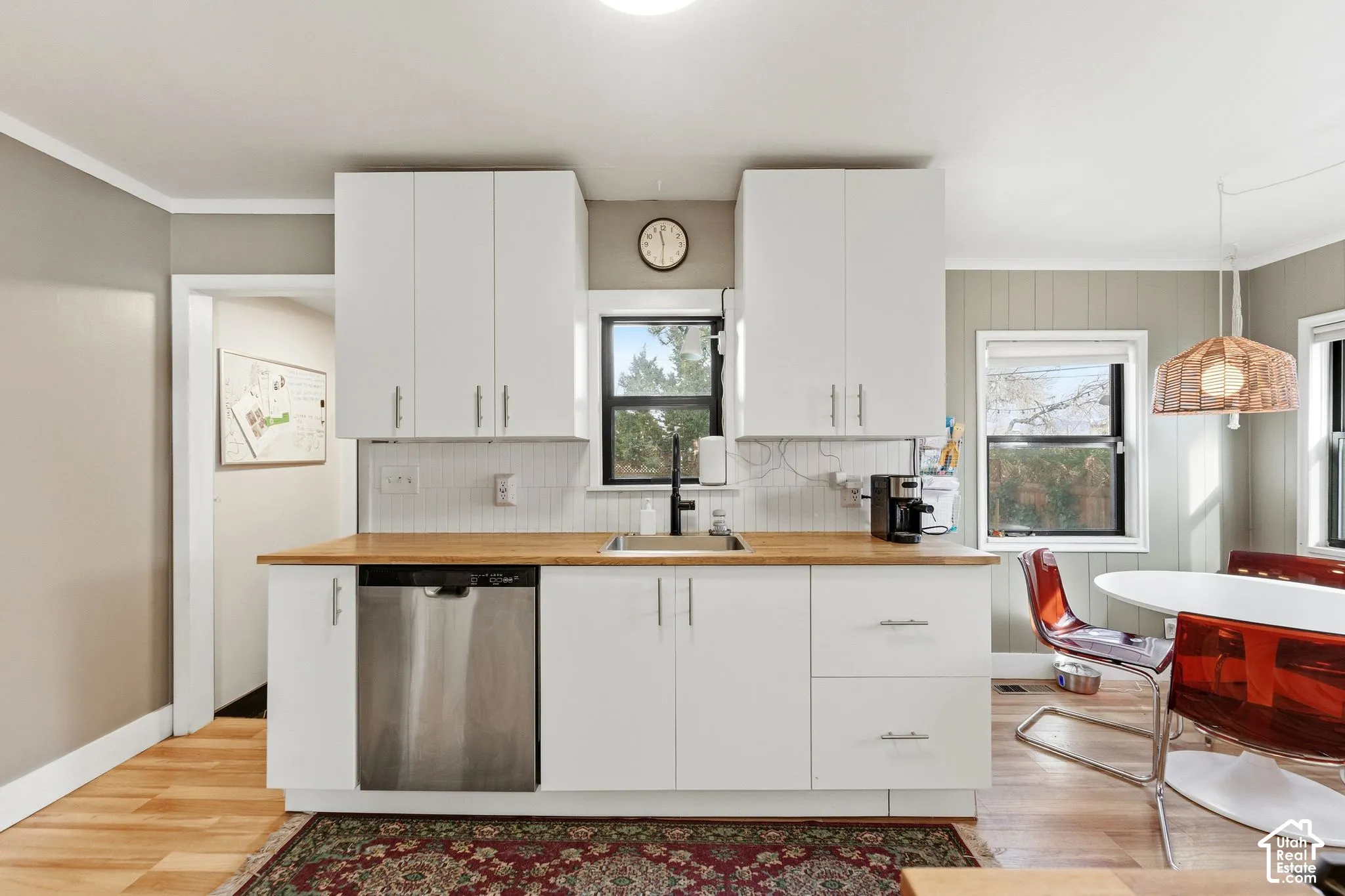 Kitchen featuring white cabinetry, wood-finish countertops, subway tile backsplash, and a stainless steel dishwasher