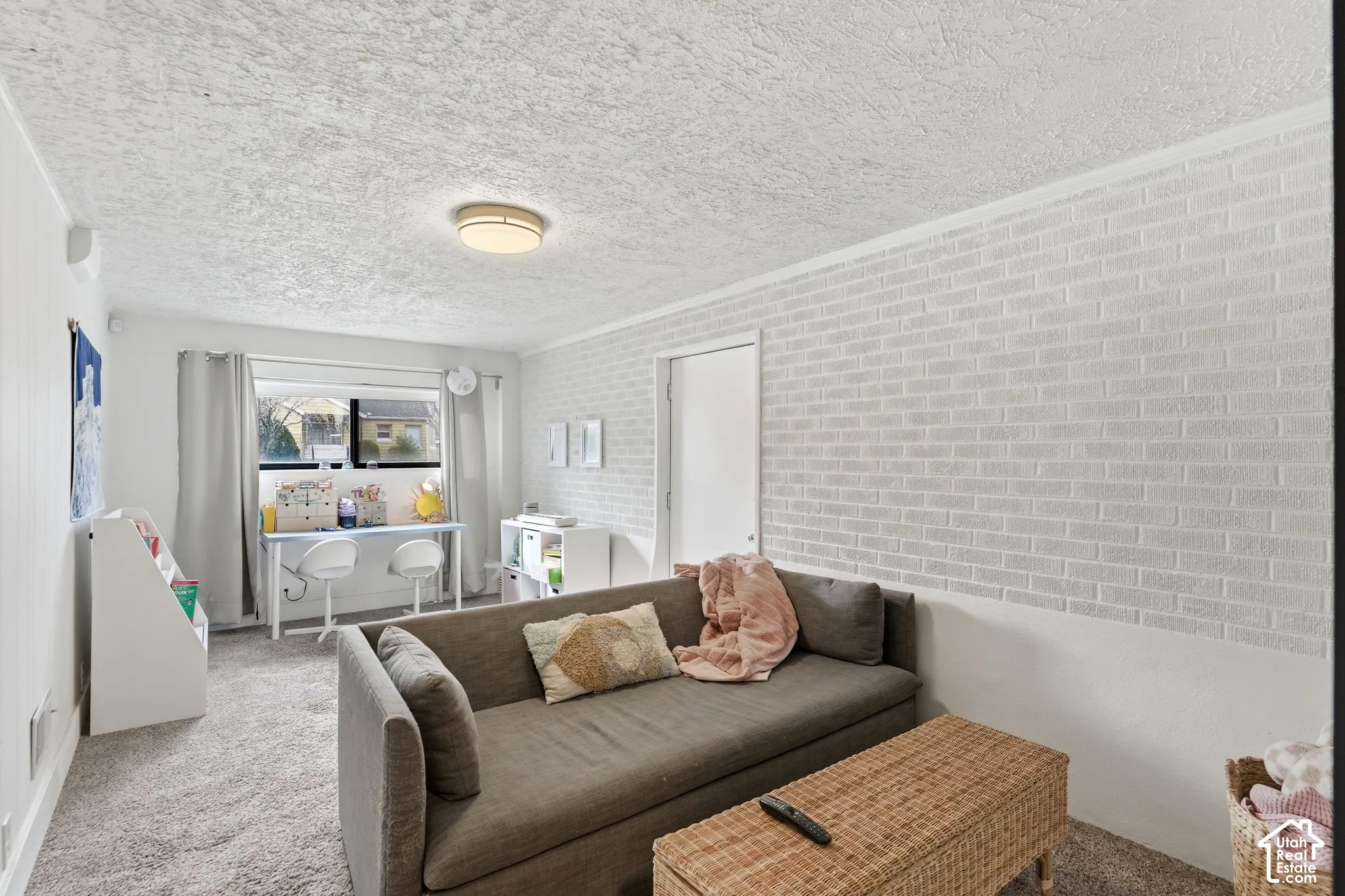 Carpeted flooring, white brick-patterned accent wall, and a ceiling-mounted light fixture
