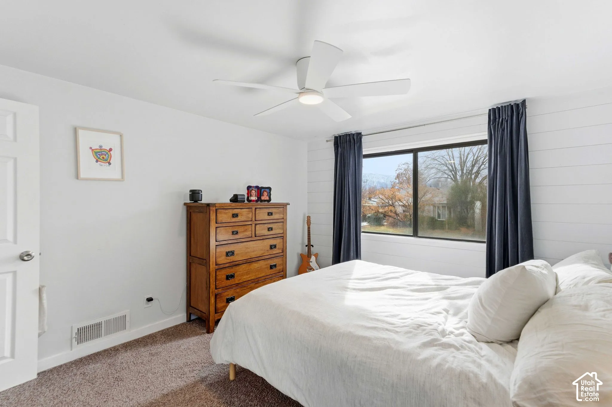 White walls with a textured accent wall, brown carpet, large window, and a ceiling fan with integrated lighting