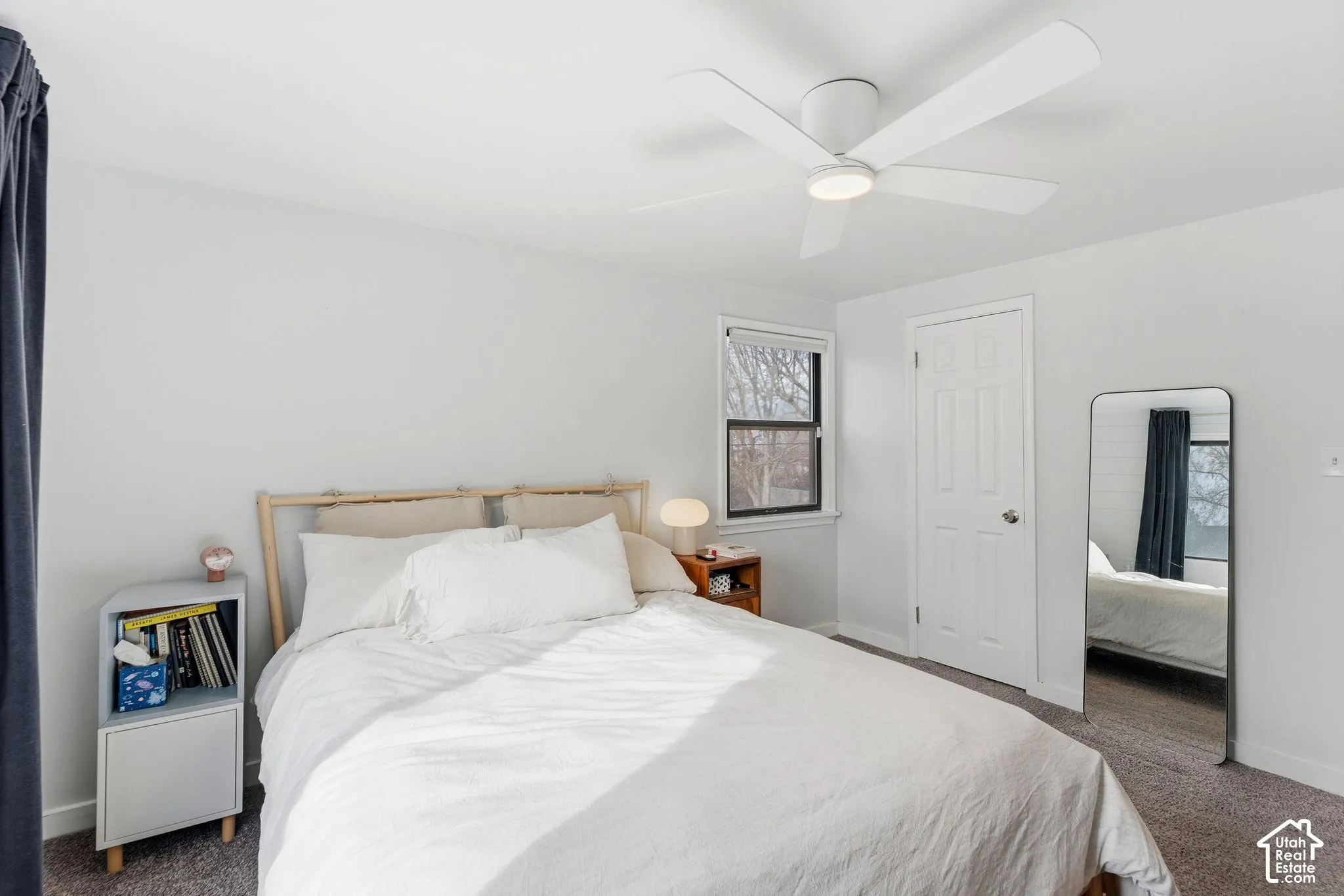 Recessed window with dark trim, overhead ceiling fan with integrated lighting, paneled door, light gray walls, and carpeting