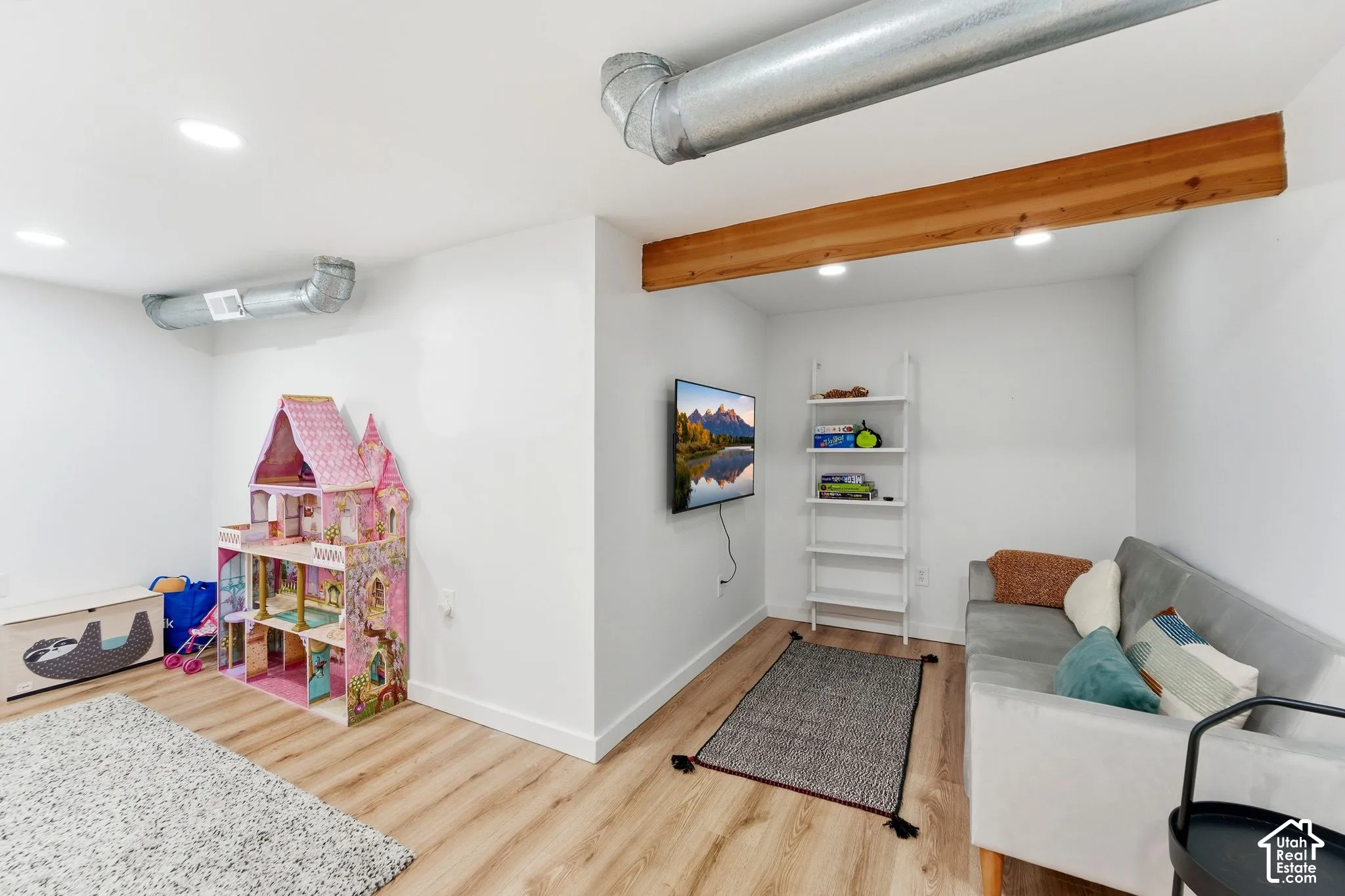 Recessed lighting illuminates the space, featuring wood-finish flooring and a natural wood beam accent