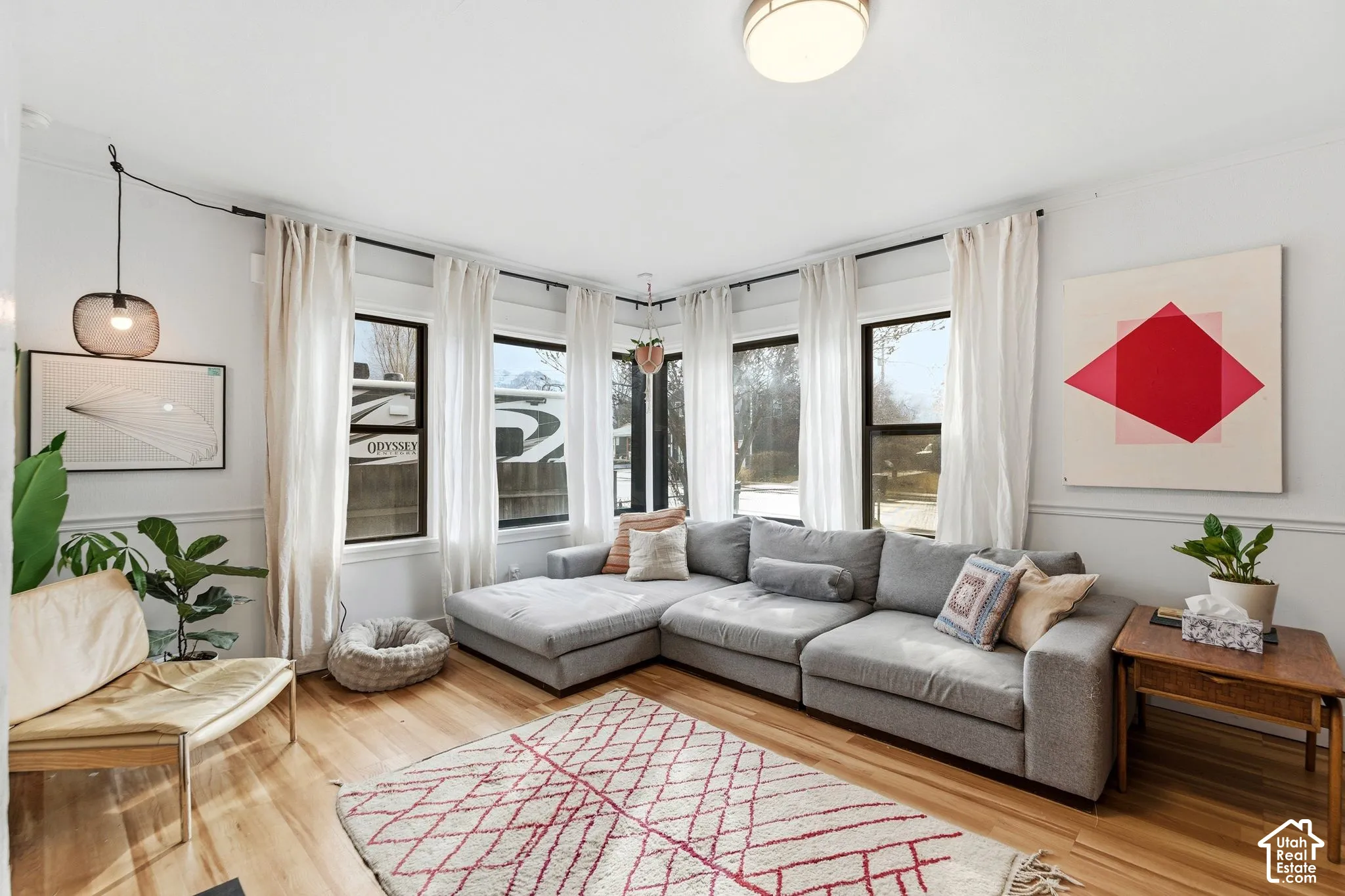 Hardwood-finish flooring, corner window configuration, recessed ceiling light, decorative wall paneling, and a contemporary ceiling light fixture