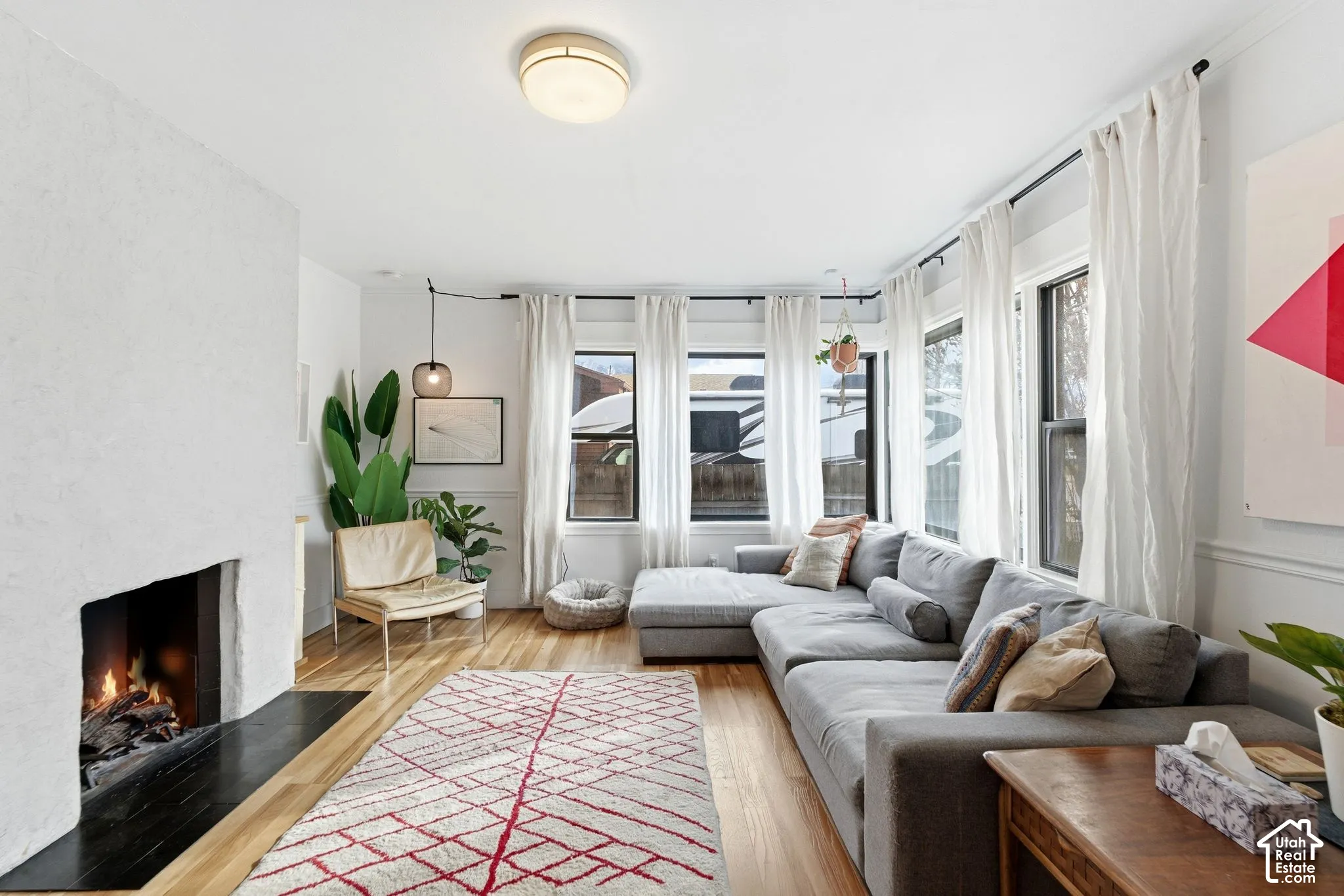Wood-finish flooring, recessed fireplace with a black hearth, multiple windows, crown molding, and a flush mount ceiling fixture