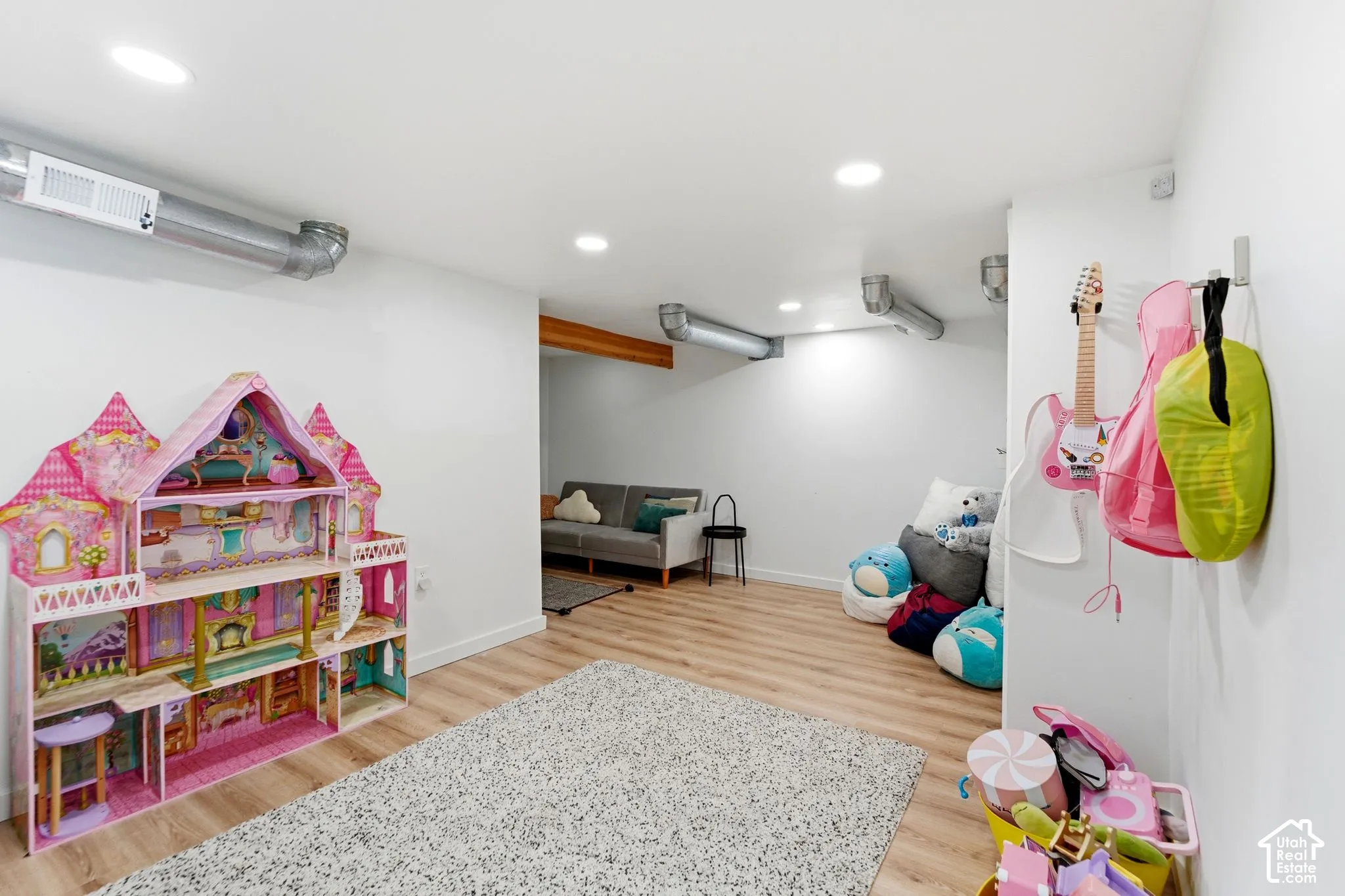 Recessed ceiling lighting, wood-finish flooring, exposed ceiling beams, white walls, and exposed ductwork