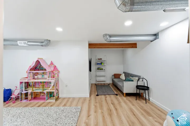 Recessed lighting, exposed ductwork, wood-finish flooring, and a structural wood beam
