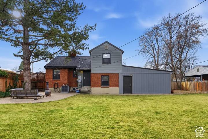 Expansive lawn area with a large mature tree, brick exterior, and a detached gray outbuilding