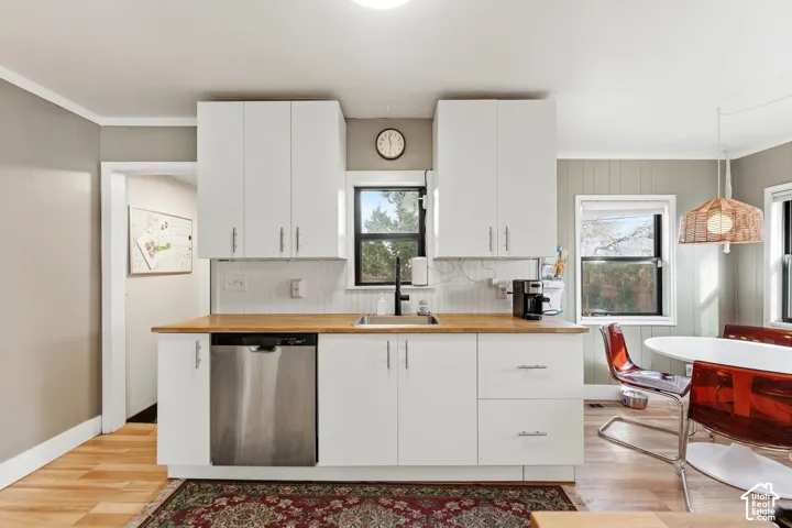 Kitchen featuring white cabinetry, wood-finish countertops, subway tile backsplash, and a stainless steel dishwasher