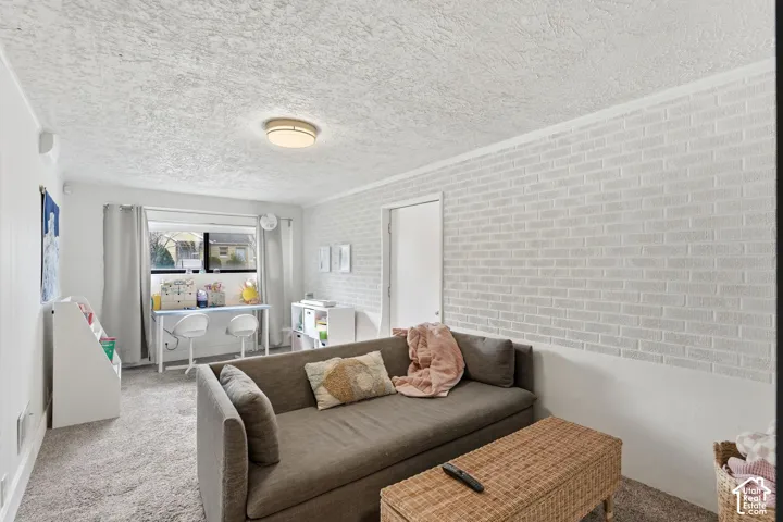 Carpeted flooring, white brick-patterned accent wall, and a ceiling-mounted light fixture