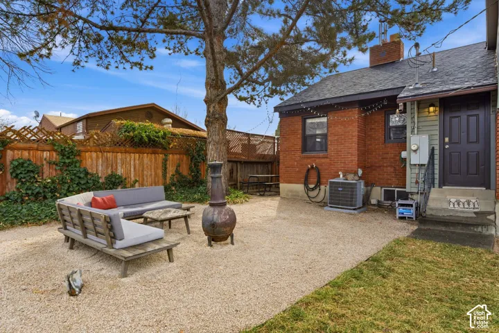 Pebble patio with a mature shade tree, privacy fencing, and brick exterior