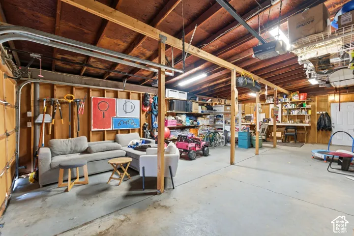 Garage space featuring exposed wood beam ceiling, concrete flooring, and built-in shelving