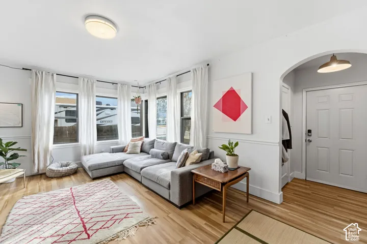 Hardwood-finish flooring throughout, featuring a series of large windows, a white paneled door, and an arched entry