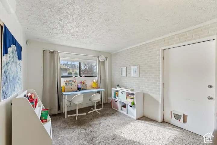 Textured ceiling, light-colored carpeting, white painted brick accent wall, and a window with curtain rods