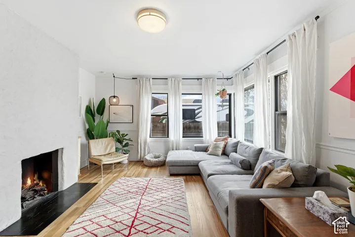 Wood-finish flooring, recessed fireplace with a black hearth, multiple windows, crown molding, and a flush mount ceiling fixture