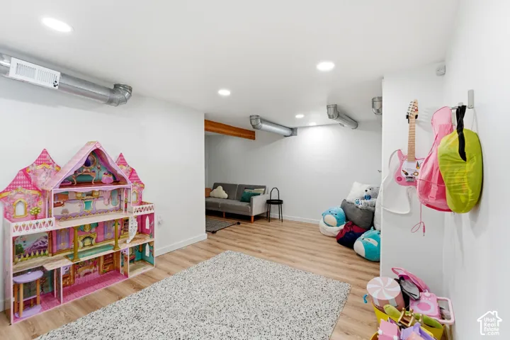 Recessed ceiling lighting, wood-finish flooring, exposed ceiling beams, white walls, and exposed ductwork