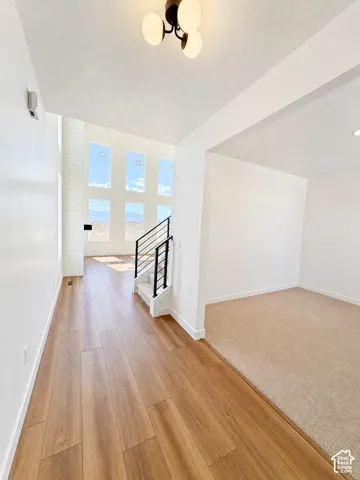 Wood-finish flooring, contemporary ceiling light fixture, geometric window design, and a staircase with black metal railings