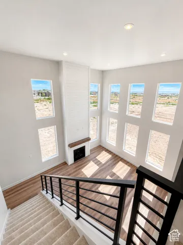 Two-story living area featuring wood-finish flooring, a contemporary fireplace with a wood mantle, and a white shiplap accent wall