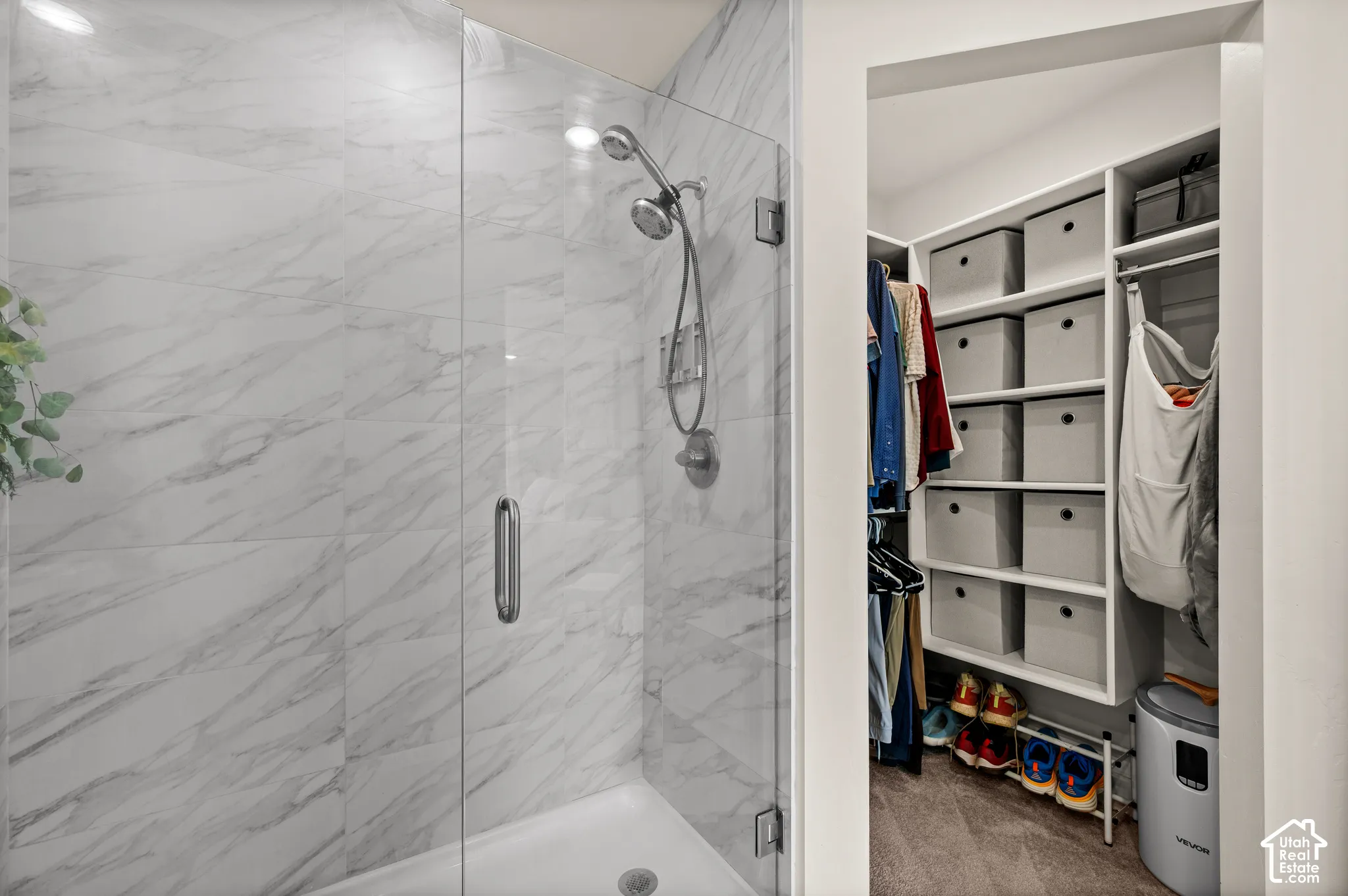 Walk-in shower with clear glass enclosure and marble-look tile surround